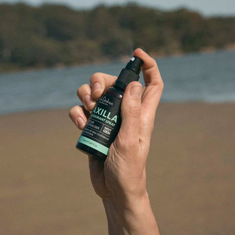 Hand holding 50ml spray bottle of Black Chicken Remedies Axilla Deodorant Spray, combining zinc with all-natural ingredients to neutralise odour, tighten pores, and soothe sensitive skin. Comes in a glass bottle.