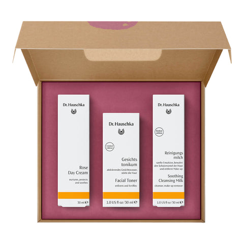 Open box of Dr Hauschka Rose Ritual Christmas Set, a 3-step morning care ritual box, featuring deluxe sample sizes of Soothing Cleansing Milk, Facial Toner, and a full size tube of Rose Day Cream. The box design is elegant and minimalistic, showcasing the brand's signature natural skincare products. The inside shows 3 boxed products.