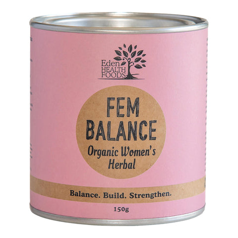 Front view of Eden Healthfoods Fem Balance Organic Women's Herbal 150g tin. The packaging is pink with a natural brown label in the centre featuring the product name. The text at the bottom reads: 'Balance. Build. Strengthen.' This formula is designed to balance female hormones and alleviate symptoms like mood swings, bloating, cramps, and sensitivity.