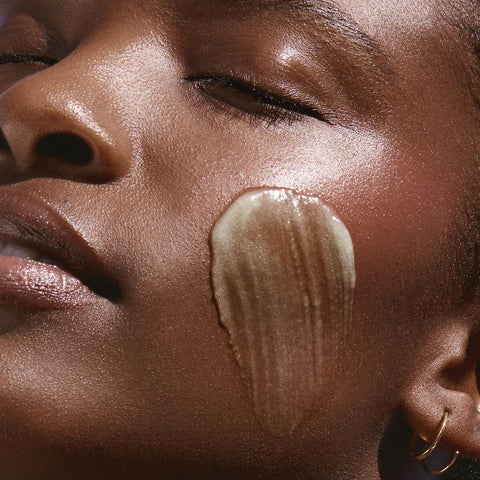 Swatch KORA Organics Active Algae Calming Cleansing Balm on a woman's cheek, showing the texture. A cleanser with microalgae, pineapple enzymes, jojoba and squalane that cleanses away makeup, dirt and oil for a clearer, more balanced complexion.