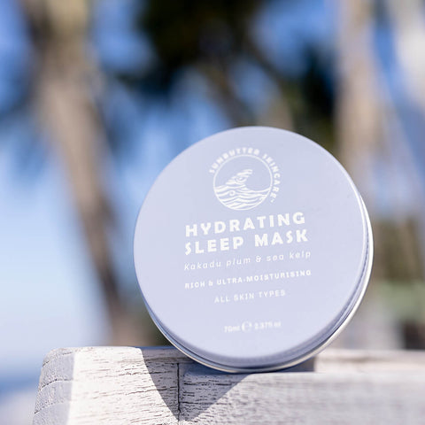 Tin of hydrating sleep mask with kakadu plum and sea kelp with palm trees in the background.