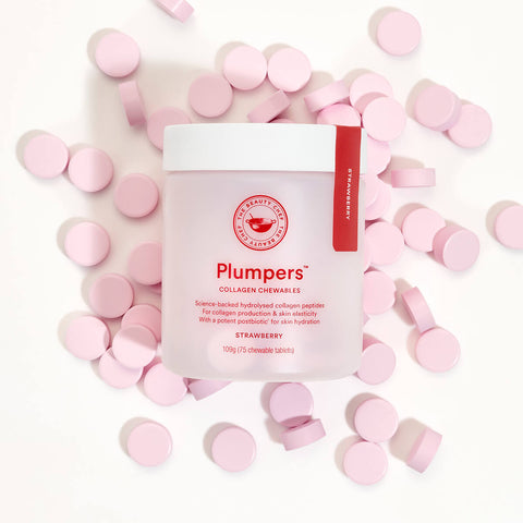 Tub of 75 chewable tablets of The Beauty Chef Plumpers Collagen Chewables in strawberry flavour. Science-backed hydrolysed collagen peptides support collagen production and skin elasticity, with a potent postbiotic for skin hydration. The plastic tub is slightly translucent white with pink text and is placed on top of scattered tablets.