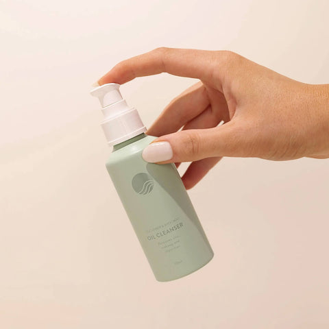 Hand holding 125ml bottle of Winki Zinc Cucumber & Avocado Oil Cleanser, designed to gently remove zinc, SPF, and makeup while leaving your skin feeling fresh faced, cleansed, and moisturised.